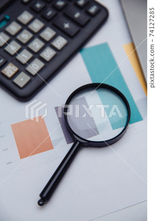 Accounting calculator, charts and magnifying glass. Business and finance concept. Vertical image Accounting calculator, charts and magnifying glass. Business and finance concept. Vertical image 74127285