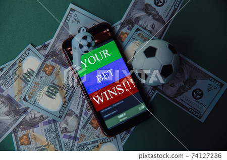 Ball, whistle and smartphone with bet application on dollar bills and green background. Gambling and bet concept. Top view Ball, whistle and smartphone with bet application on dollar bills and green background. Gambling and bet concept. Top view 74127286