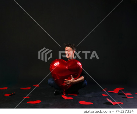 valentines red heart, an inflatable balloon in hands, handsome heterosexual. On a black background beauty greeting, 74127334