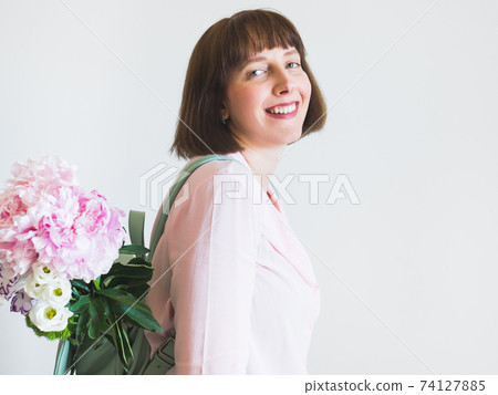 Young woman in pink with backpack and peony bouquet 74127885