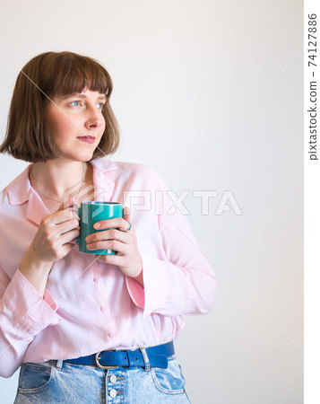 Young woman wearing pink shirt drinking coffee 74127886