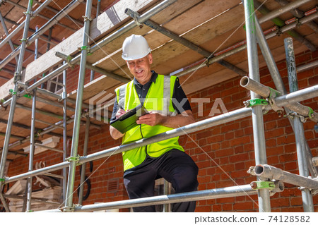 Male Builder Construction Worker Contractor on Building Site With Clipboard Male Builder Construction Worker Contractor on Building Site With Clipboard 74128582