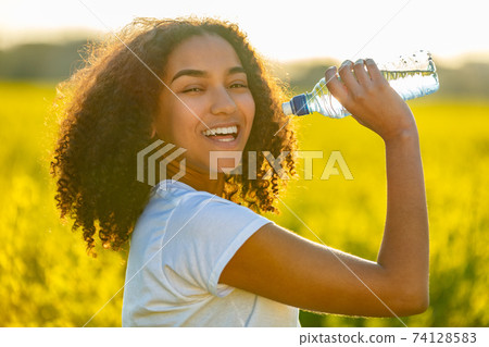 Mixed Race African American Girl Teenager Drinking Water at Sunset 74128583