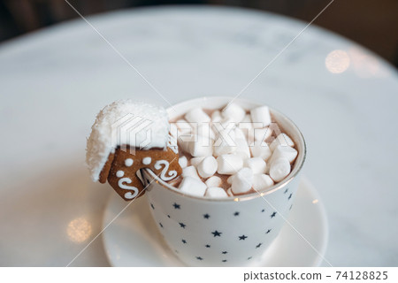 The mug with the christmas decorations and cookie on edge The mug with the christmas decorations and cookie on edge 74128825