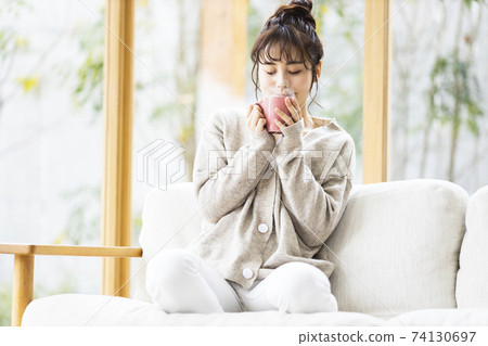 A woman drinking a hot drink 74130697