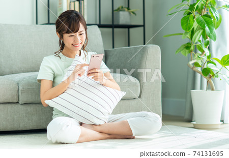 年輕女子在客廳看智慧型手機 74131695