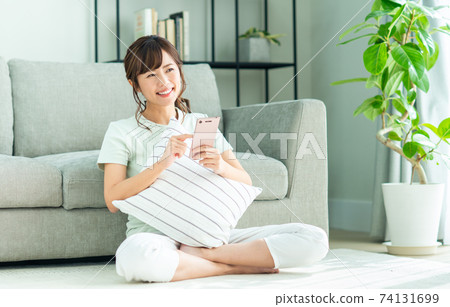 Young woman looking at her smartphone in the living room Young woman looking at her smartphone in the living room 74131699
