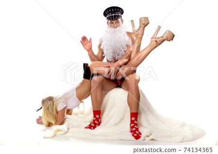 Man in Santa outfit slapping buttock of woman 74134365