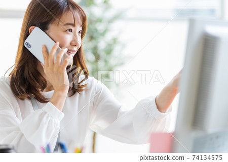 A woman talking on her smartphone during desk work 74134575