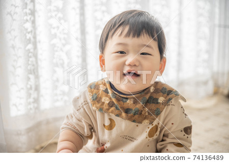 Baby sitting by the window and playing with the remote control Baby sitting by the window and playing with the remote control 74136489