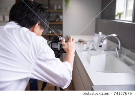 A male photographer taking a picture of a product in the kitchen photographer 74137679