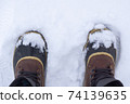 Top view of anonymous traveler in warm boots standing on white snow on winter day. 74139635