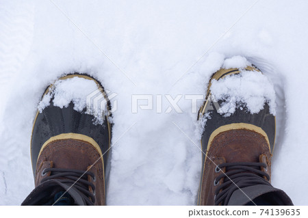 Top view of anonymous traveler in warm boots standing on white snow on winter day. Top view of anonymous traveler in warm boots standing on white snow on winter day. 74139635