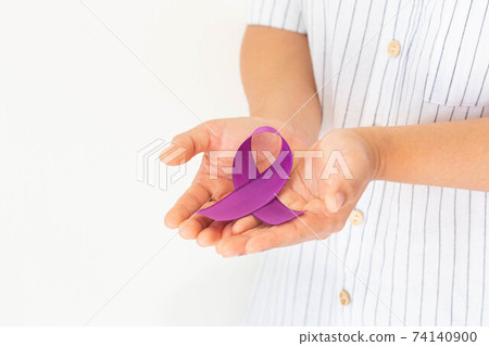 Hands holding purple or violet ribbon on white background, copy space. Pancreatic Cancer ,Testicular Cancer Awareness, Cancer Survivor, Leiomyosarcoma, World Cancer Day. Healthcare, insurance concept. 74140900