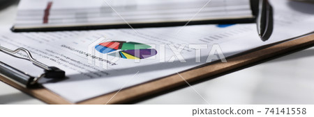 Financial statistics documents on clipboard pad 74141558