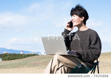 A man talking while looking at a computer outdoors 74141608
