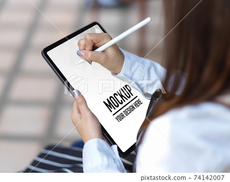 Female using digital tablet  with stylus pen in blurred background 74142007