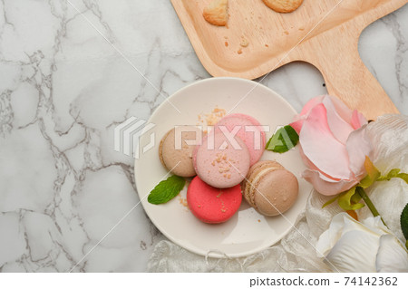 Marble dinning tabla with a plate of French colourful macarons decorated with roses flower Marble dinning tabla with a plate of French colourful macarons decorated with roses flower 74142362