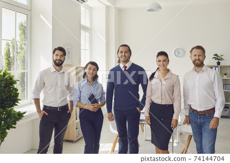 Successful smiling business people coworkers standing and looking at camera in office 74144704