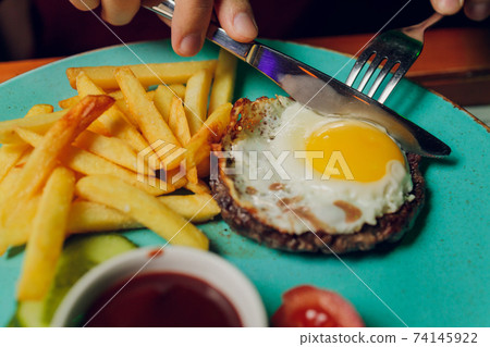 Grilled steaks, French fries, fried egg and vegetables. Grilled steaks, French fries, fried egg and vegetables. 74145922