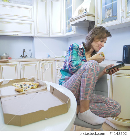 girl using smartphone while sitting at home in her kitchen  74148202