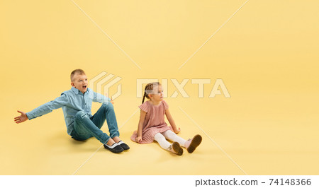 Childhood and dream about big and famous future. Boy and girl isolated on yellow studio background 74148366