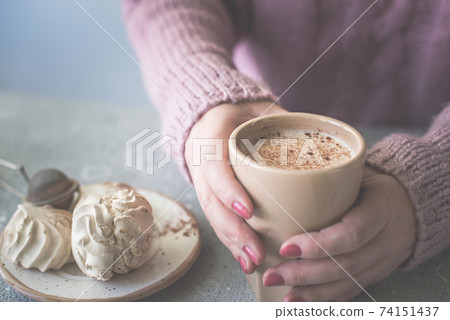 Women in a warm sweater hold a cup coffee or cocoa. Women in a warm sweater hold a cup coffee or cocoa. 74151437