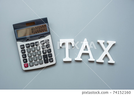 TAX text with calculator on gray background. investment and time to tax concepts 74152160