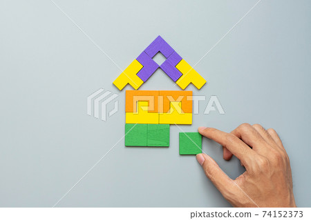 hand connecting Home shape block with colorful wood puzzle pieces on gray background. logical thinking, business logic, solutions, rational, house, real estate and strategy concepts 74152373