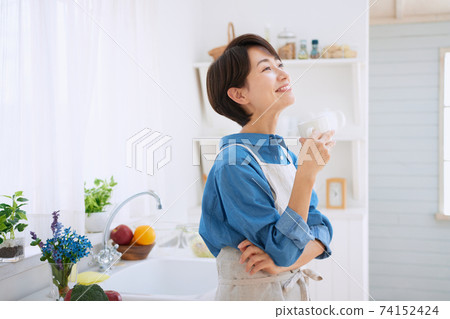 Middle woman relaxing in the kitchen Middle woman relaxing in the kitchen 74152424