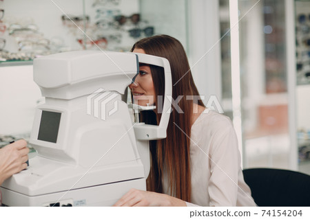 A woman doctor and patient doing opthalmology check vision test by refractometer 74154204