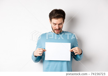 Excited bearded guy reading banner on blank piece of paper, showing logo, standing over white background Excited bearded guy reading banner on blank piece of paper, showing logo, standing over white background 74156723