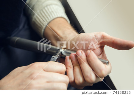 Close up hands of jeweller, goldsmiths making of golden ring with gemstone using professional tools. 74158235