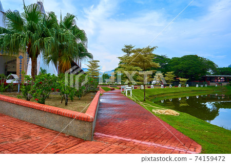The gardener set aside a hose for watering plants on the lawn in the park 74159472