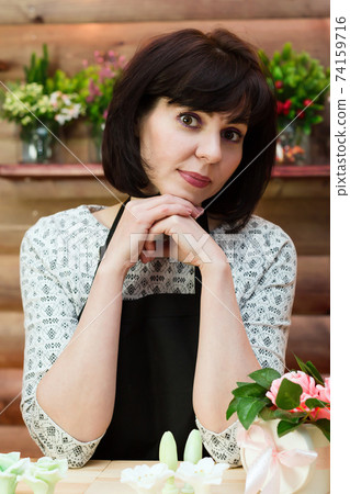 Bored woman flower shop clerk stands behind the counter Bored woman flower shop clerk stands behind the counter 74159716