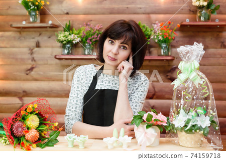Bored woman flower shop clerk stands behind the counter Bored woman flower shop clerk stands behind the counter 74159718