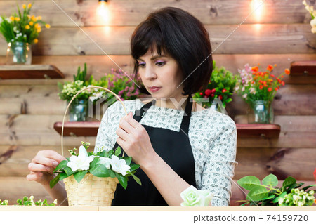 Woman in apron at her workplace in flower shop Woman in apron at her workplace in flower shop 74159720