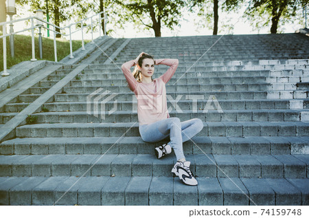 woman sitting on stairs relaxing before running woman sitting on stairs relaxing before running 74159748