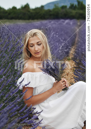 Beautiful woman in a white dress on a lavender field in Provence 74160954
