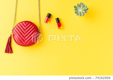 Red woman purse on background with nail polishes and flower. Flat lay Red woman purse on background with nail polishes and flower. Flat lay 74162009