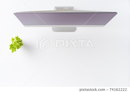 Overhead shot of computer with green flower on white table. Office desktop concept. Flat lay 74162222