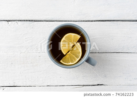 Overhead shot of cup of tea with silce of lemon on white wooden table 74162223