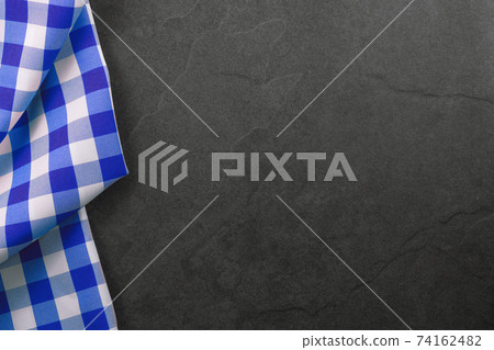 Classic cooking background - blue checkered tablecloth on a vintage black stone kitchen countertop with copy space 74162482