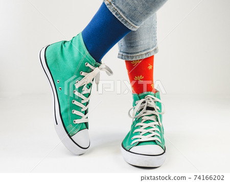 Green sneakers and funny socks on a white background 74166202