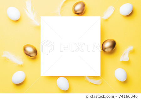 Easter border. Golden, white colour egg on pastel yellow background in Happy Easter decoration. Flat lay, top view. 74166346