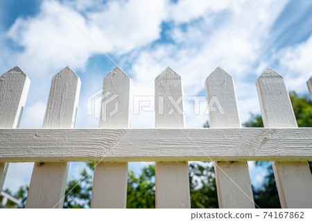 White picket fence under a blue sky 74167862