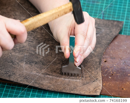 craftsman punches a leather detail for handbag 74168199