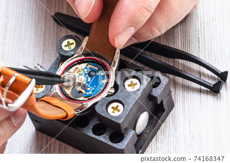 watchmaker replaces battery in quartz wristwatch 74168347