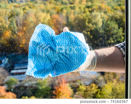 male hand washes home window glass by blue rag male hand washes home window glass by blue rag 74168367