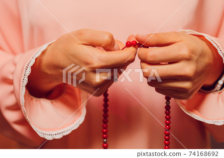 Concentrated woman praying wearing rosary beads. Namaste. Close up hands. Concentrated woman praying wearing rosary beads. Namaste. Close up hands. 74168692